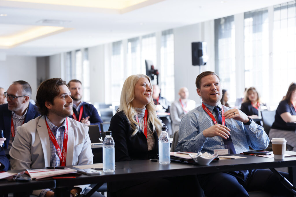 Fischer Group associates attend a sales counselor training session, seated at tables with notepads, water bottles and smiling as they listen.