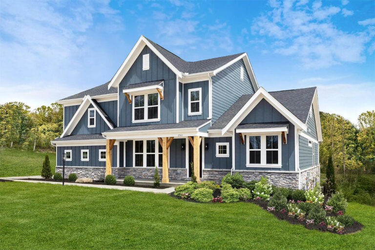 Two-story blue craftsman-style house built by Fischer Homes featuring white trim, gabled roof, and manicured front lawn under a blue sky.